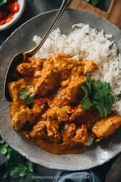 a close up of a plate of food with rice and meat in sauce on the side