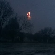 an exit sign is lit up in the night sky above a parking lot with snow on the ground