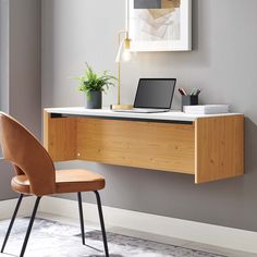 a desk with a laptop on it next to a chair and potted plant in the corner