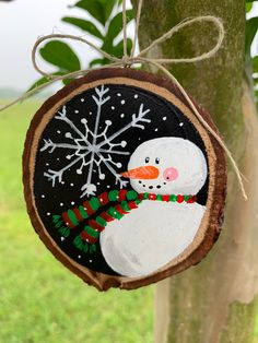 a wooden ornament with a snowman on it hanging from a tree branch