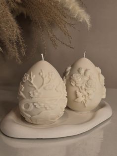 two white candles sitting on top of a plate