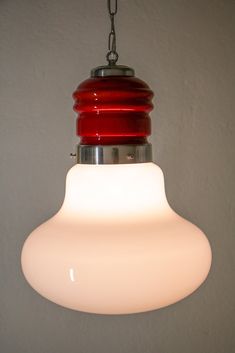 a red and white light hanging from a ceiling fixture with a chain attached to it