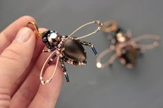 a person is holding a tiny insect brooch in their hand