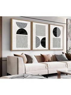 three black and white paintings hanging on the wall above a couch in a living room