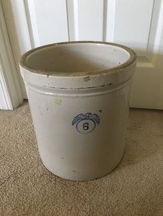 a white bucket sitting on top of a carpeted floor next to a door way