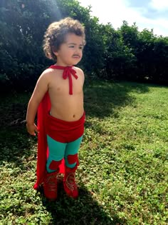 a small child wearing red and green pants with a tie around it's neck