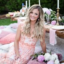 a woman in a pink dress sitting on the ground with flowers and candles around her