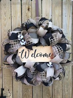 a welcome wreath hanging on the side of a wooden fence