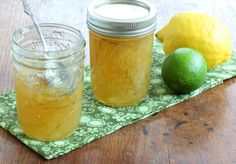 two jars filled with liquid sitting on top of a wooden table next to lemons