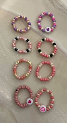 six bracelets with pink, white and black beads on top of a bed sheet