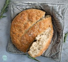 a loaf of bread sitting on top of a blue and white towel next to rosemary sprigs