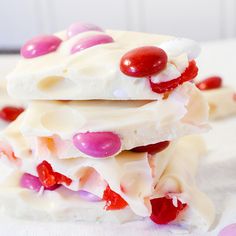 three pieces of white chocolate with red and pink candies on top are stacked together