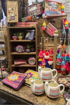 an assortment of colorful items on display in a market stall, including mugs and books