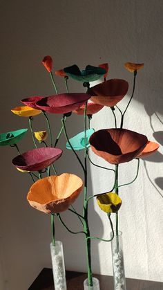 three vases with flowers in them sitting on a table next to a wall and window