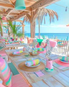 the table is set with colorful plates and place settings for an outdoor dining area overlooking the ocean