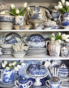 blue and white china with tulips in vases, plates and bowls on shelves