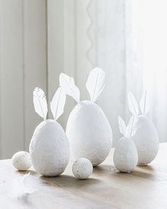 three white paper mache eggs sitting on top of a wooden table next to each other