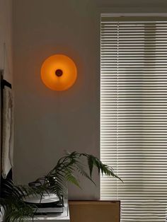 an orange light hanging from the side of a wall next to a window with blinds