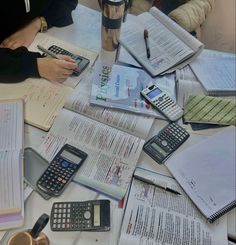 several people sitting at a table with books and calculators on top of them