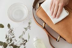 a woman cleaning her handbag with a cloth on the table next to some flowers