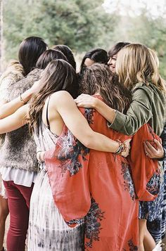 a group of women standing next to each other in front of a forest filled with trees