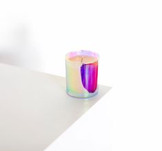 a rainbow colored candle sitting on top of a white table