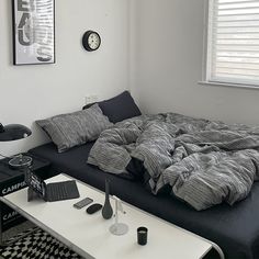 a black and white room with a bed, coffee table, alarm clock and pictures on the wall