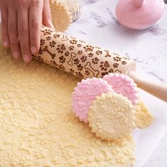 a person is rolling out cookies on a cookie sheet with a rolling pin next to it