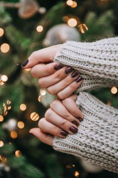 two hands holding each other in front of a christmas tree with lights on the branches