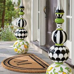 three black and white vases sitting on top of a door mat next to a doorway