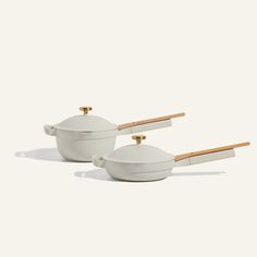 two white bowls with wooden handles and lids