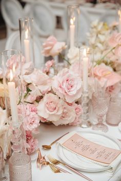 a table topped with lots of pink flowers and candles