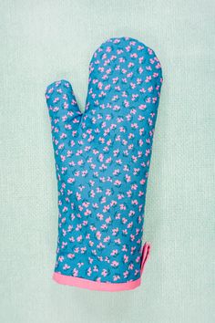 a blue oven mitt with pink flowers on it sitting on top of a green surface