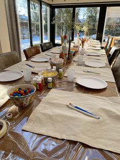 a long table is set up with plates, bowls and utensils on it