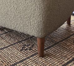 an upholstered chair with wooden legs on a rug