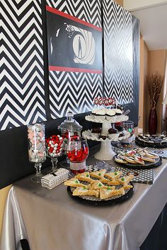 a table topped with lots of food next to a wall covered in black and white chevrons