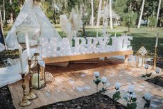 a wooden table topped with white letters and lit candles next to a teepee tent