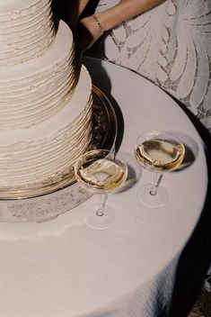 a wedding cake and two glasses of wine on a table