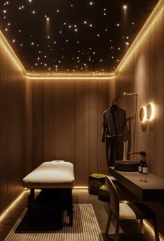 a dimly lit room with a bed, desk and chair in the corner under stars on the ceiling