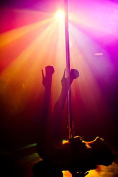 a person sitting on the ground holding onto a pole with their hands in the air