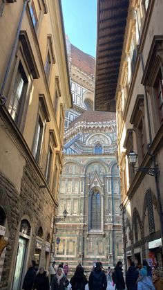 several people are walking down an alley way with buildings in the background and one person is looking up at the sky