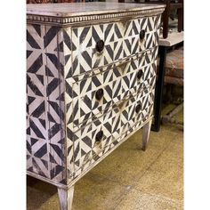 an old dresser is decorated with black and white geometric designs on the top, along with other pieces of furniture