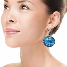 a woman wearing blue earrings with an ocean scene on the front and back of her ear