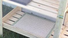 a close up of a chicken coop with grass and wood flooring on the ground