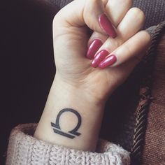 a woman's hand with a tattoo on her wrist and the letter q in black ink