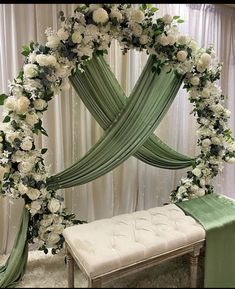 a wedding arch decorated with white flowers and greenery