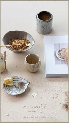 a table topped with bowls filled with food next to a book and cupcakes