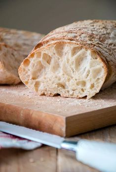 a loaf of bread sitting on top of a wooden cutting board next to a knife