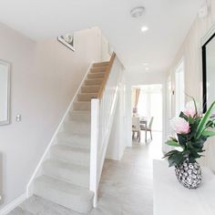 there is a vase with flowers on the table next to the stairs in this house