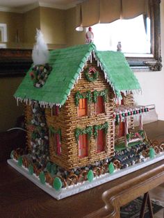 a gingerbread house decorated with icing and decorations on top of a wooden table